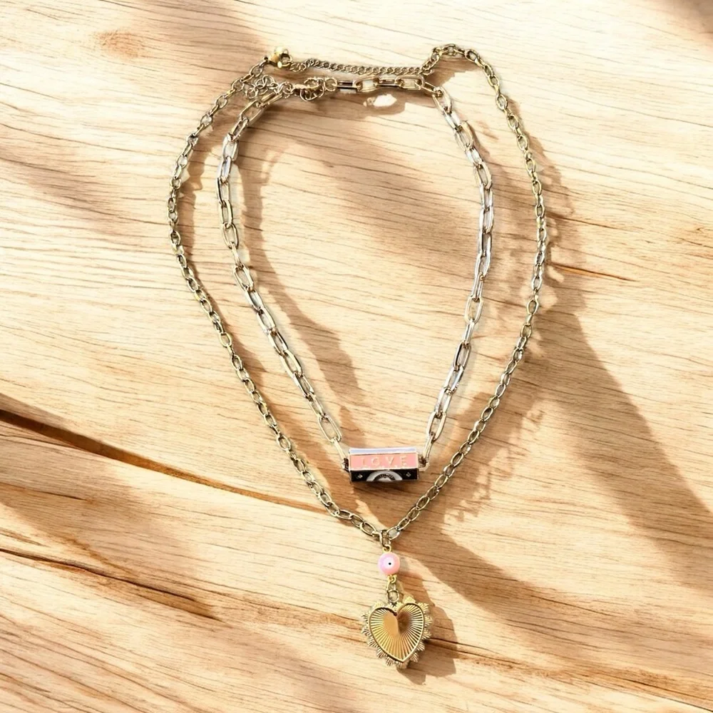 Gold toned chains with black, white, gold, and pastel pink enamel charms.